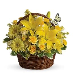 Yellow flowers arranged in a wicker basket with a butterfly accent