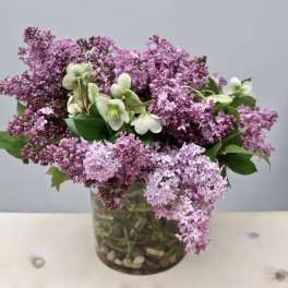 Lilac bouquet with white hellebore in a glass vase