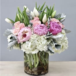 Pink and white bouquet in a glass vase with peonies, roses, and hydrangeas