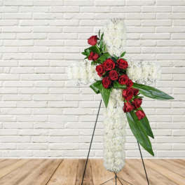 White floral cross with red roses on a stand