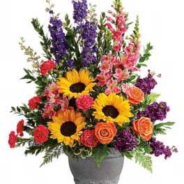 Colorful bouquet with sunflowers, roses, and purple blooms in a gray vase