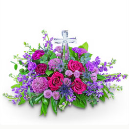 Purple and pink floral arrangement with a clear cross centerpiece