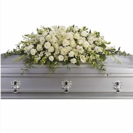 White floral casket spray with roses, calla lilies, and greenery