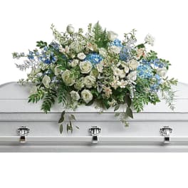 White and blue floral casket spray with greenery