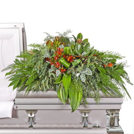 Large floral casket spray with red blooms and mixed greenery on a silver casket