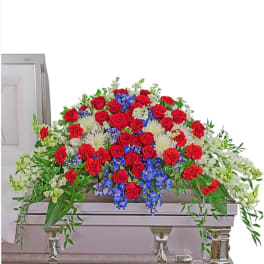 Red roses, blue flowers, and white blooms arranged on a casket