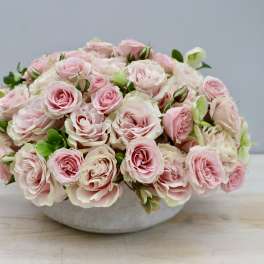 Low bowl arrangement of pale pink roses in a white container