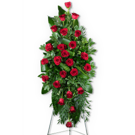 Tall standing spray of red roses with lush greenery on a black easel