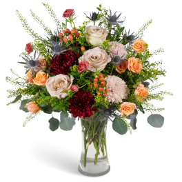 Mixed bouquet of roses, chrysanthemums, and thistle in a clear glass vase