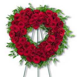 Heart-shaped wreath of red roses with green foliage on a stand