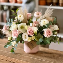 Pink and white roses in a blush vase with airy dried grasses