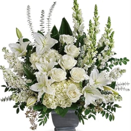 White lilies and roses arranged in a gray urn vase