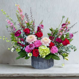 Mixed bouquet in a dark round vase with red, pink, and white flowers