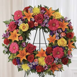 Colorful floral wreath on a black easel with roses, lilies, and daisies