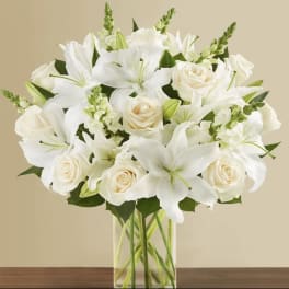 White lilies and cream roses in a clear glass vase