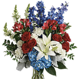 Bouquet of red roses, white lilies, blue flowers, and white blooms in a glass vase