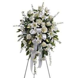 White floral standing spray on an easel with a ribbon