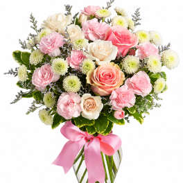 Pink and cream rose bouquet in a glass vase with a pink ribbon