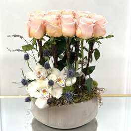 Pink roses and white orchids arranged in a round vase