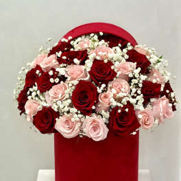Red and blush roses arranged in a red hat box