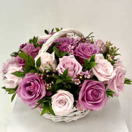 Basket of pink and lavender roses with small filler flowers