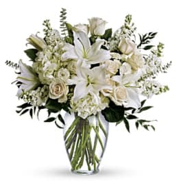 White lilies and roses arranged in a clear glass vase