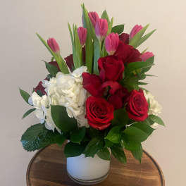 Bouquet of red roses, pink tulips, and white hydrangeas in a white vase