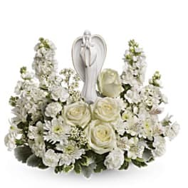 White floral arrangement with roses and a praying angel figurine