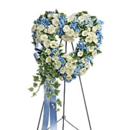 Heart-shaped floral wreath on a standing easel with blue and white flowers