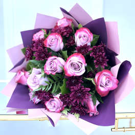 Bouquet of pink roses and dark purple chrysanthemums wrapped in purple paper