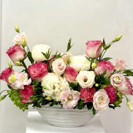 Pink and white floral arrangement in a white bowl vase