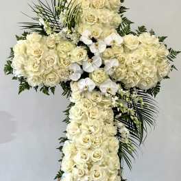 Cross-shaped floral spray of white roses and orchids on an easel