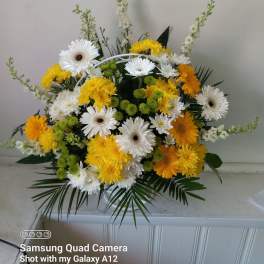 Yellow and white mixed flower arrangement in a clear vase