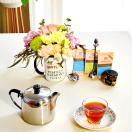 Flower arrangement in a mug with tea bags, teapot, and a cup of tea