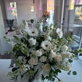 White floral arrangement with roses and daisies tied with a white ribbon