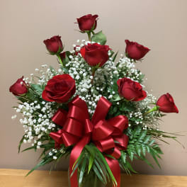 Red roses in a vase with baby's breath and a large red ribbon