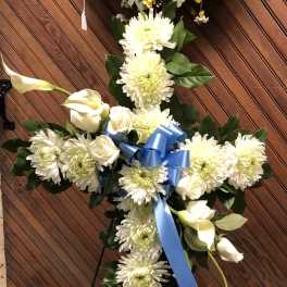White floral cross with blue ribbon on an easel