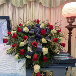 Red and white rose spray on a blue casket with a ribbon