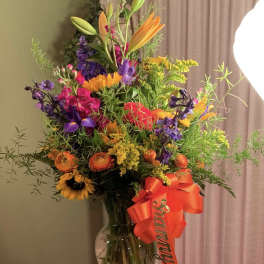 Colorful mixed bouquet in a glass vase with a red ribbon