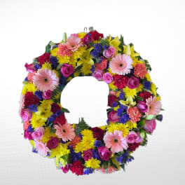 Circular wreath of mixed pink, yellow, purple, and red flowers