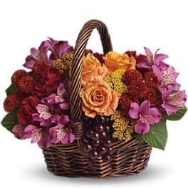 Basket of orange roses and purple flowers