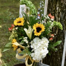 Bouquet of sunflowers, white lilies, and white hydrangea in a glass vase