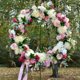 Large floral wreath with pink and white flowers on a metal stand