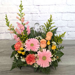 Pink gerberas and peach roses arranged with snapdragons in a low container.