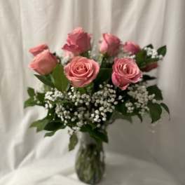 Pink roses arranged in a clear glass vase with white filler flowers
