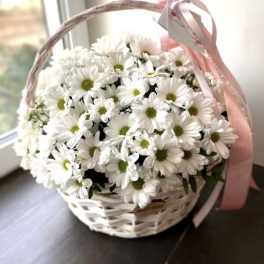 White daisy bouquet in a white wicker basket with a pink ribbon