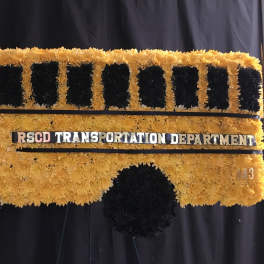 Yellow and black floral display shaped like a bus with a transportation sign