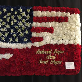 Floral tribute arranged as an American flag with red, white, and blue flowers.