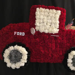 Red and white floral arrangement shaped like a vintage truck