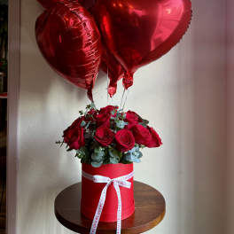 Red roses in a round box with red heart balloons above